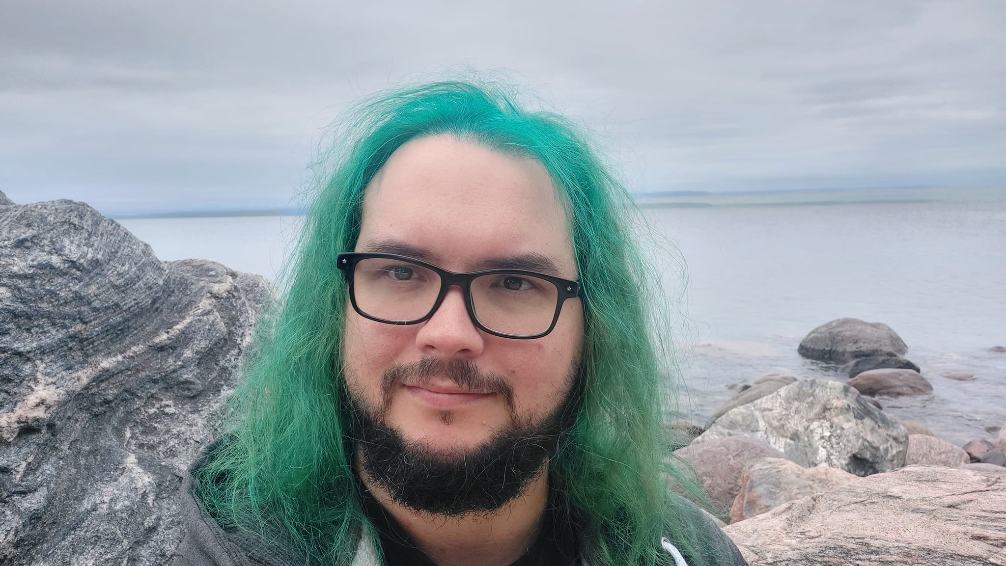 A man with green hair stands outside at a boulder breakwater, photo 13